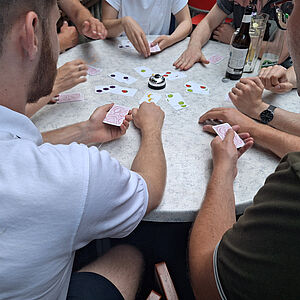 Blick auf einen runden Tisch, es wird von mehreren Personen gespielt