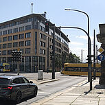 Fahrzeuge stehen vor roter Signalanlage, zwei Straßenbahnen überfahren in gegensätzlicher Richtung die Kreuzung