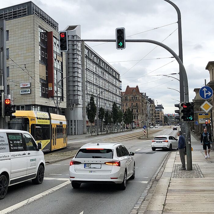 Straßenbahn befährt die Haltestelle Kongresszentrum, Fahrzeug biegt bei grünen Pfeil rechts ab, Fußgänger und Fahrradweg rechts auf dem gemeinsamen Rad- und Gehweg