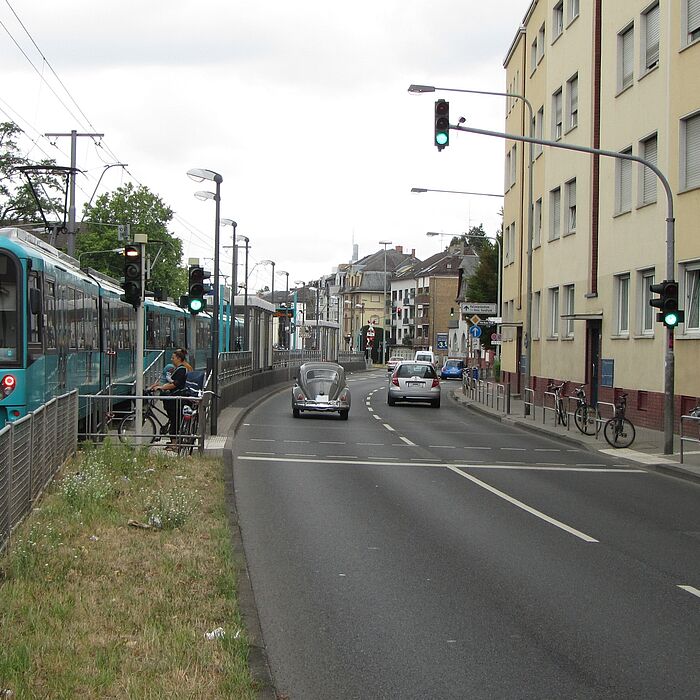 zweistreifige Richtungsfahrbahn mit rechts liegender Wohnbebauung und links Strecke ÖPNV (Fahrzeug der U8)