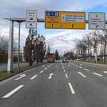 Richtungsfahrbahn mit mehreren Abbiegestreifen, darüber Schilderbrücke mit Wegweisung