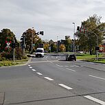 Straßeneinmündung mit Ampel und STOPP-Beschilderung, Radfahrer wartet, im Hintergrund Bebaung und Kirchtürme