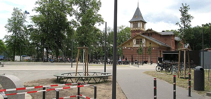 Blick auf das historische Eierhäuschen mit Außengastronomie, Wege, Fahrräder, Personen 