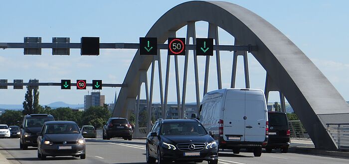 Blick direkt auf der Brücke stehend in den Verkehr, Brückenbogen im Hintergrund, über den Fahrzeugen VBA