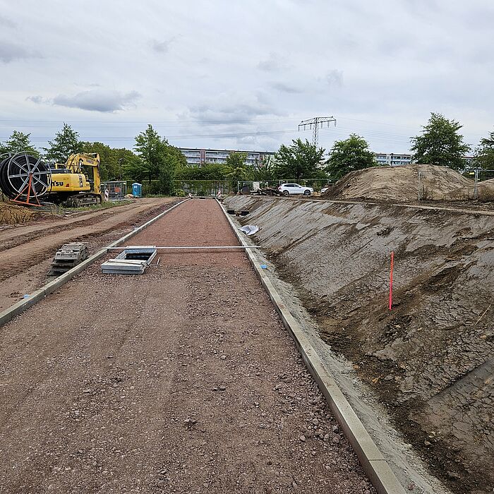 Wegebau im Südpark Blick auf Weg im Bau mit rechtseitiger unbewachsener Böschung, Trommel mit Leitung im Hintergrund