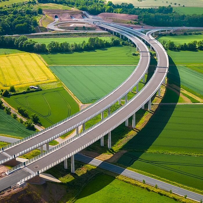 Blick von oben auf die Wehretalbrücke als zweistegige Spannbeton-Plattenbalken-Ausführung im Hintergrund Weiterführung als Tunnel, im Vordergrund darunter kreuzende Straße