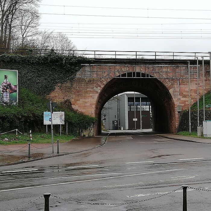 bestehende Bogenbrücke mit rötlichen Naturstein mit unterführender Straße, Bahnstrecke über die Brücke