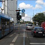 Kreuzungsbereich, Straßenbahn und Fahrzeuge fahren parallel über die Kreuzung, Gebäude im Hintergrund