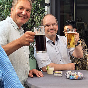 zwei Personen prosten mit Bier