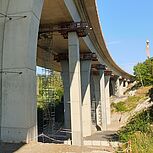 Blick auf die Konstruktion der Brücke von unten und auf die Stützen, Blick auf die Baustelle mit Gerüsten und Kran im Hintergrund