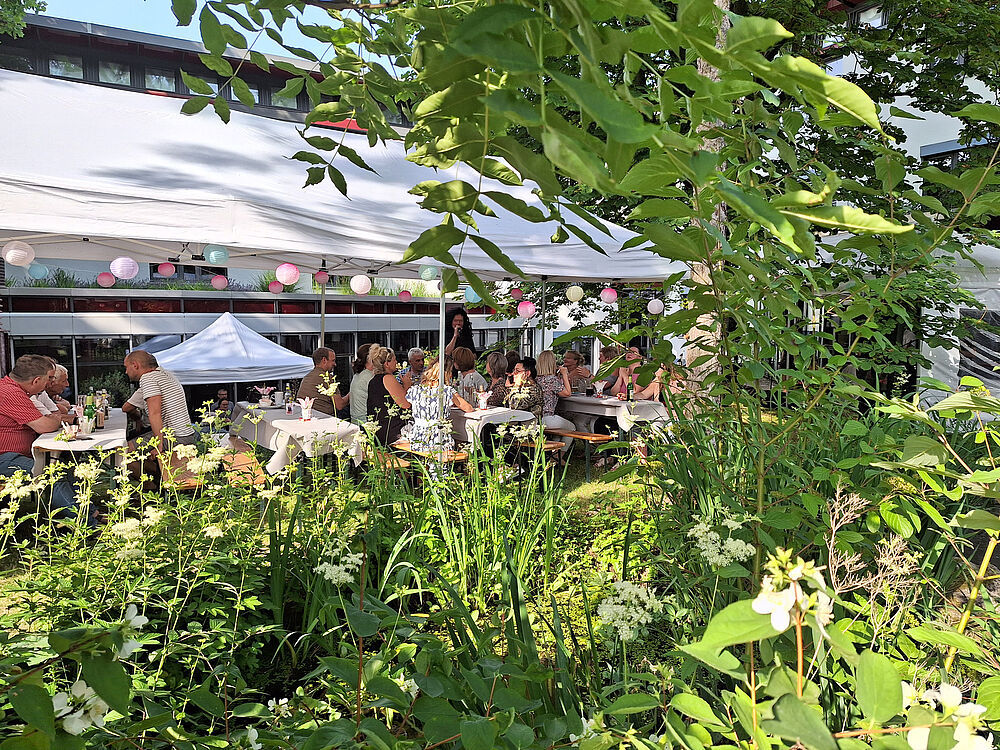 kleines Festzelt mit Personen im Hintergrund, im Vordergrund Vegetation