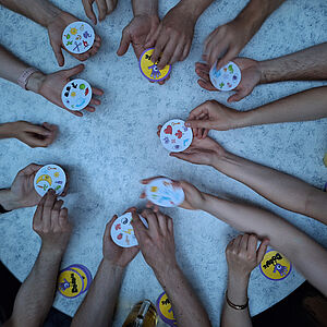 Blick von oben auf den Spieltisch, viele Spielkarten und Hände