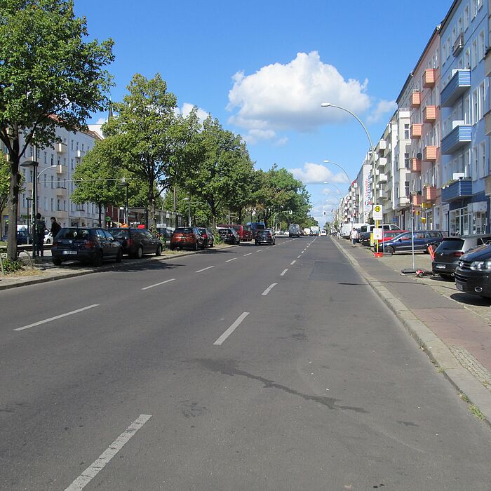 Fahrbahn mit parallelen Radweg, direkt anschließend Parkbereich und Bebauung